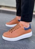 Brown sneakers with a blue accent worn by a person on a tiled floor.