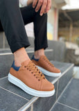 Brown sneakers with white soles worn by a person on stone steps.